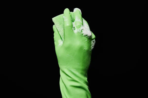 Vista recortada del hombre en guante de goma verde que sostiene la esponja aislada en negro - foto de stock