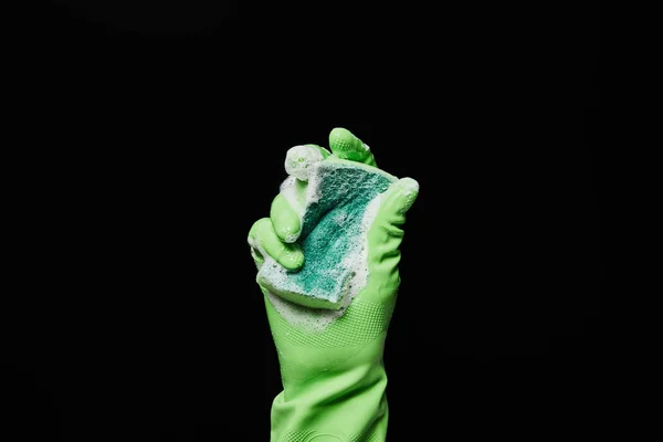 Vue recadrée de l'homme en gant de caoutchouc vert tenant éponge isolé sur noir — Photo de stock