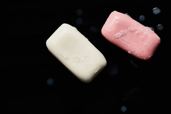 Top view of pink and white soaps with drops on black background — Stock Photo