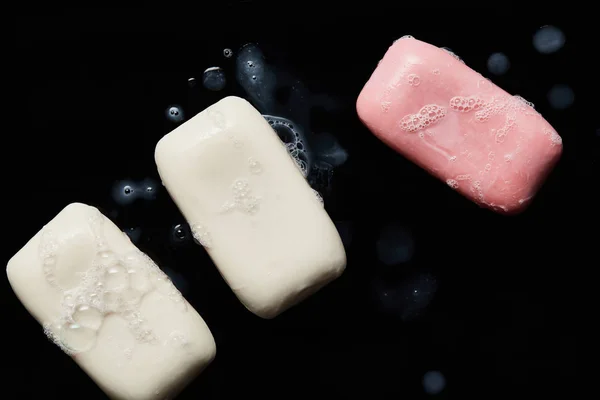 Top view of pink and white soaps with drops on black background — Stock Photo