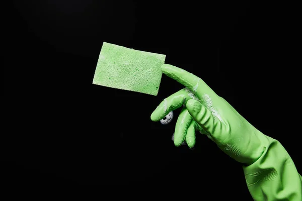 Vista recortada del hombre en guante de goma verde con esponja sobre fondo negro - foto de stock
