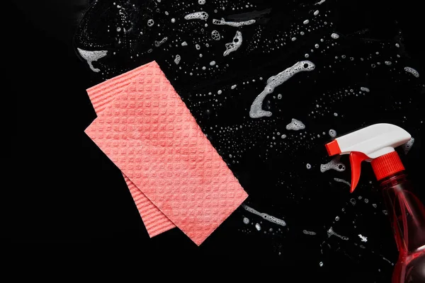 Top view of pink rag and bottle with spray on black background — Stock Photo