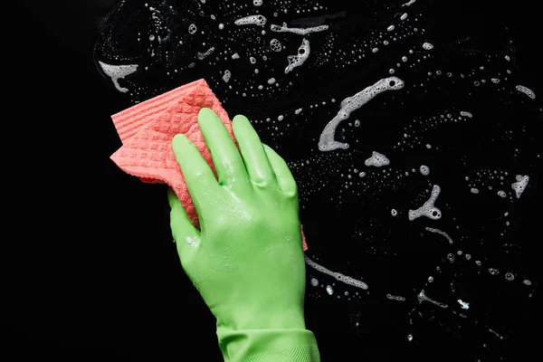 Cropped view of man in rubber glove cleaning with pink rag on black background — Stock Photo