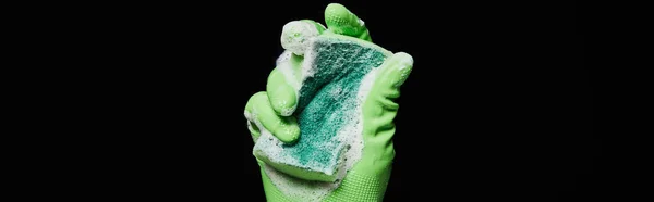 Panoramic shot of man in rubber glove holding colorful sponge isolated on black — Stock Photo