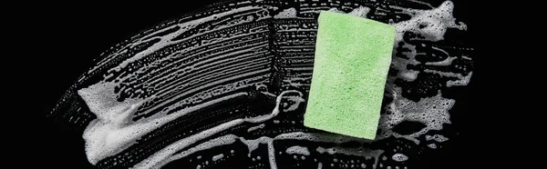 Panoramic shot of green and colorful sponge with foam on black background — Stock Photo