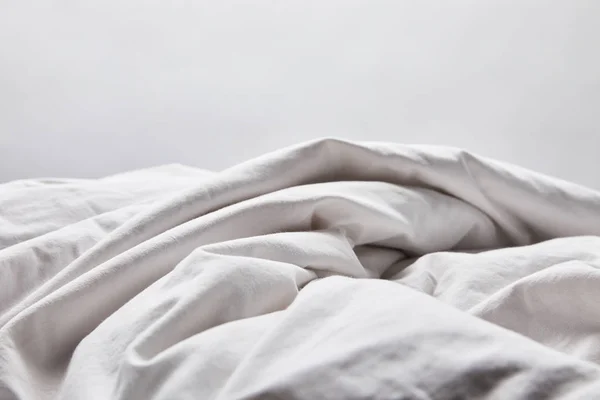 Crumpled white blanket in bed isolated on grey — Stock Photo