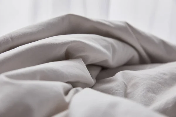 Crumpled cotton white blanket in bed at morning — Stock Photo