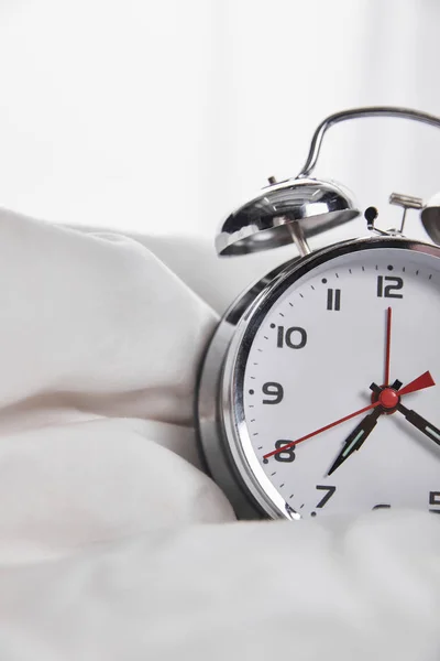 Close up vista de relógio de alarme de prata na cama branca — Fotografia de Stock