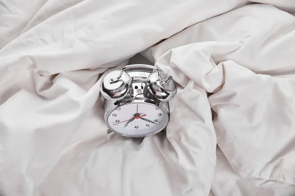 Ansicht des silbernen Weckers im weißen Bett — Stockfoto