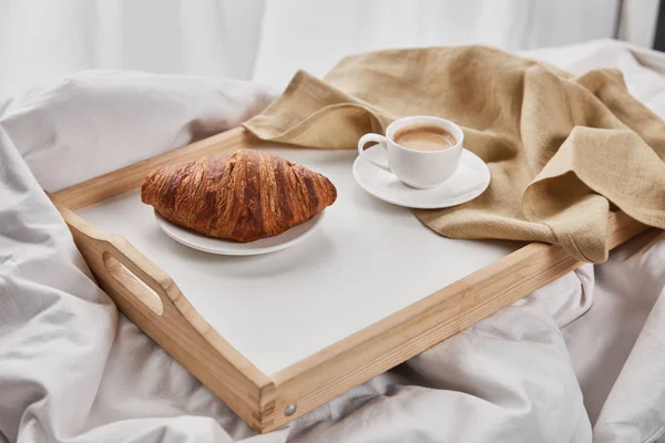 Cruasán fresco con café en bandeja de madera con servilleta - foto de stock