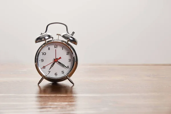 Relógio de alarme de prata na mesa marrom de madeira isolado em cinza — Fotografia de Stock