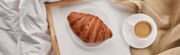 Vista superior de croissant fresco com café em bandeja de madeira na cama de manhã, tiro panorâmico — Fotografia de Stock