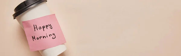 Top view of coffee to go and sticky note with happy morning lettering on beige background, panoramic shot — Stock Photo