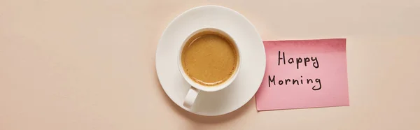 Top view of coffee and sticky note with happy morning lettering on beige background, panoramic shot — Stock Photo