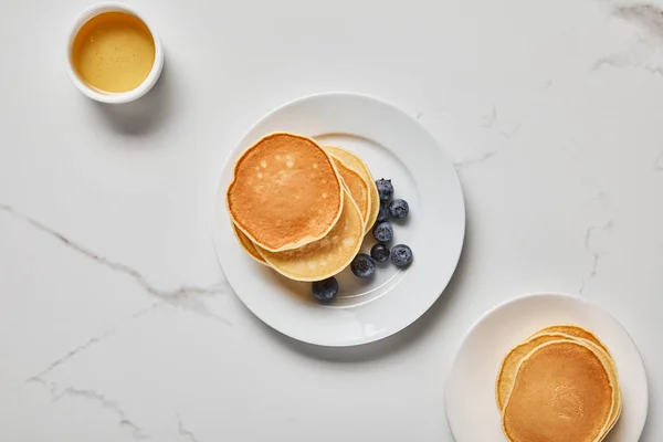 Top view of bowl with honey near plates with pancakes — Stock Photo