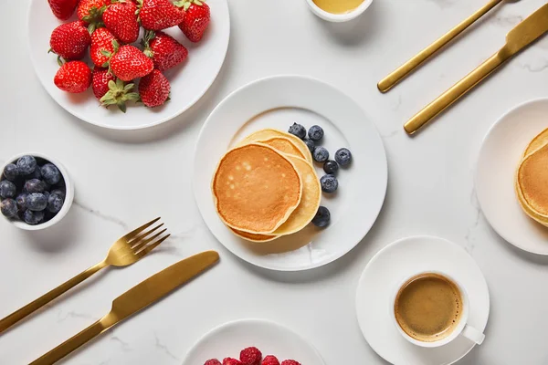 Blick von oben auf das servierte Frühstück mit Beeren, Pfannkuchen und Kaffee — Stockfoto