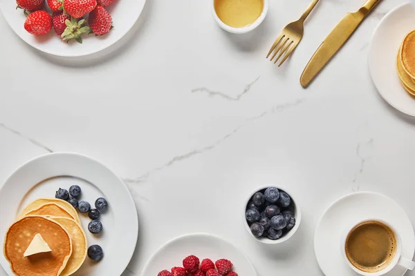 Blick von oben auf leckeres Frühstück mit Pfannkuchen, Honig, verschiedenen Beeren und Kaffee — Stockfoto