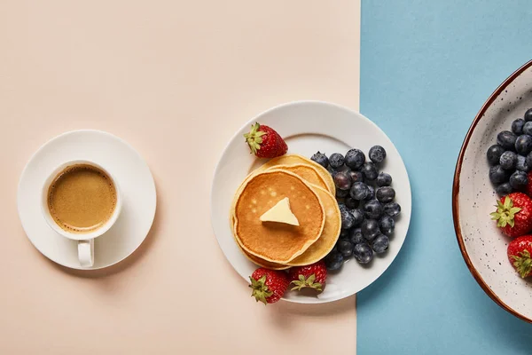 Top view of pancakes with berries on plate near cup of coffee — Stock Photo