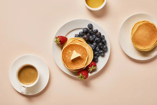 Von oben auf Pfannkuchen mit Beeren, in der Nähe Tasse Kaffee und Schüssel mit Honig auf rosa — Stockfoto