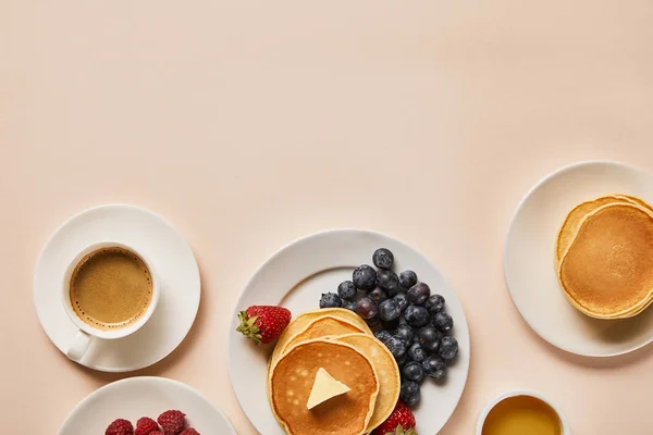 Vista superior del delicioso desayuno servido con panqueques, bayas, miel y café - foto de stock