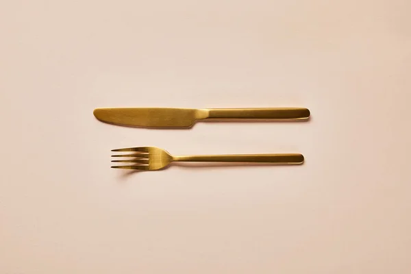 Top view of golden fork and knife on pink background — Stock Photo