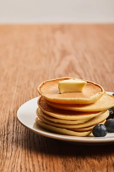 Selective focus of pancakes with butter on plate on wooden surface — Stock Photo