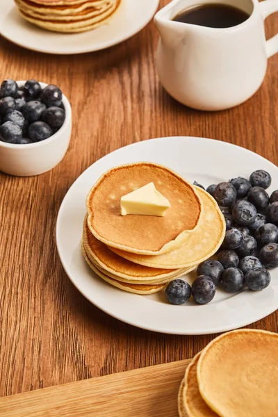 Colazione con pancake, burro, mirtilli e sciroppo su superficie di legno — Foto stock