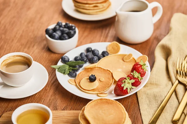 Top view of pancakes with berries on plate, syrup in jug, honey and coffee, bear concept — Stock Photo