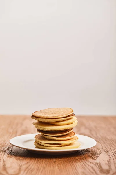 Panquecas saborosas para o café da manhã na placa branca na superfície de madeira isolada no cinza — Fotografia de Stock