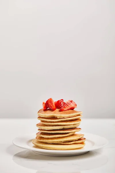 Tortitas para el desayuno con fresas en plato blanco aislado en gris - foto de stock