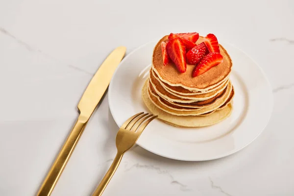 Golden cutlery on plate with pancakes and strawberries — Stock Photo