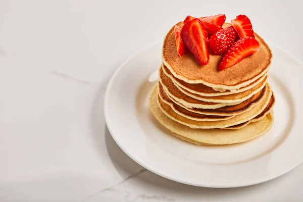 Tasty pancakes for breakfast with strawberries on white plate on textured surface — Stock Photo