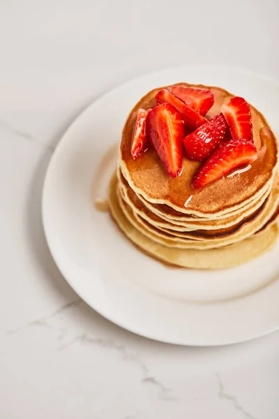 Tasty pancakes with strawberries and syrup on white plate on textured surface — Stock Photo