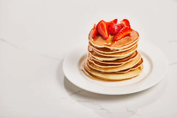 Teller mit Pfannkuchen, Erdbeeren und Sirup auf strukturierter Oberfläche — Stockfoto