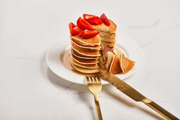 Goldenes Besteck auf Teller mit Pfannkuchen mit Erdbeeren auf strukturierter Oberfläche — Stockfoto