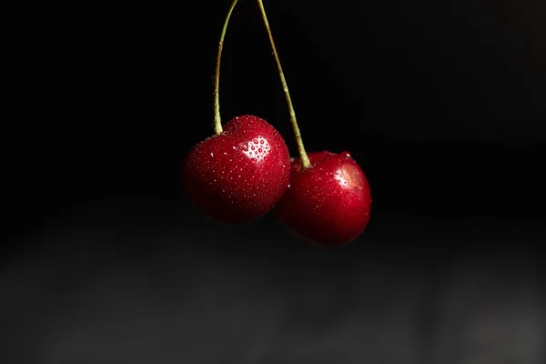 Vista de cerca de deliciosas cerezas húmedas con gotas de agua aisladas en negro - foto de stock