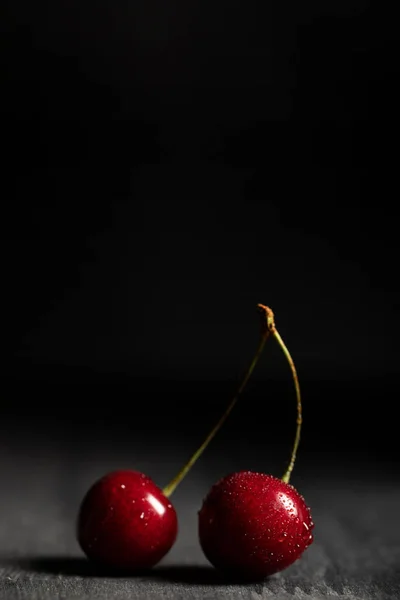 Vue rapprochée de cerises rouges délicieuses avec gouttes d'eau sur table en bois isolé sur noir — Photo de stock