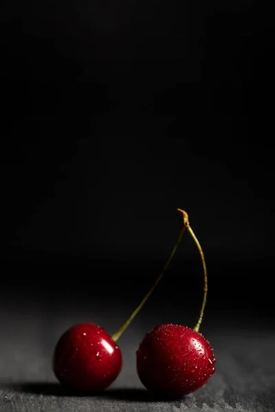 Close up view of red delicious cherries with water drops on wooden table isolated on black — Stock Photo