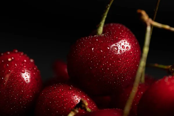 Vista de cerca de rojo deliciosas cerezas brillantes con gotas de agua aisladas en negro - foto de stock