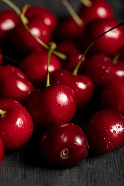 Vista de cerca de cerezas rojas deliciosas y maduras con gotas de agua en la mesa de madera - foto de stock