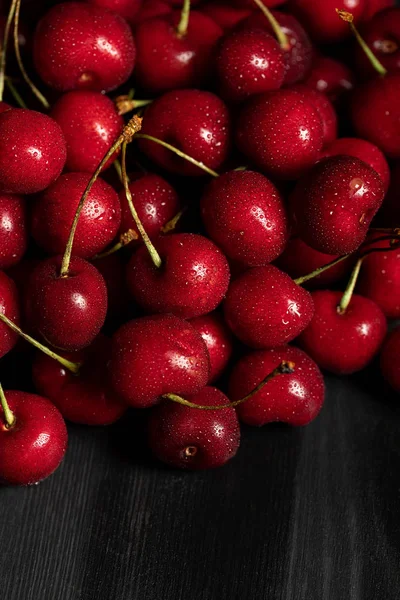 Vista de cerca de cerezas rojas deliciosas y maduras con gotas de agua en la mesa de madera - foto de stock