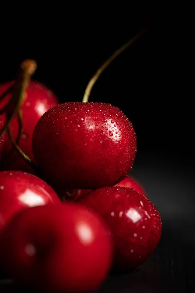 Close up view of red tasty and ripe cherries with water drops on black background — Stock Photo