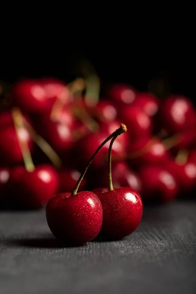 Selective focus of red delicious sweet cherries on wooden table isolated on black — Stock Photo
