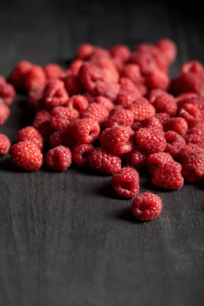 Selektiver Fokus von leckeren reifen Himbeeren auf Holztisch verstreut — Stockfoto