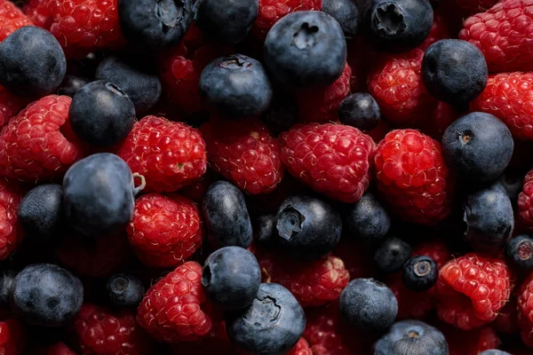 Vue rapprochée de délicieuses framboises et bleuets mûrs et frais mélangés — Photo de stock