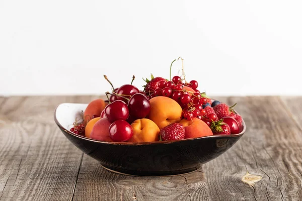 Prato com deliciosas bagas maduras misturadas em mesa de madeira isolada em branco — Fotografia de Stock