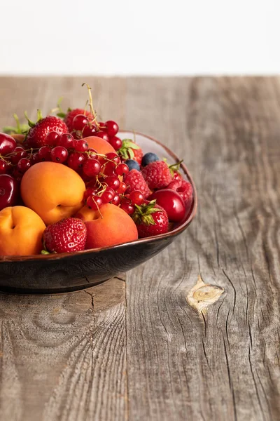 Close up view of plate with mixed delicious ripe berries on wooden table isolated on white — Stock Photo