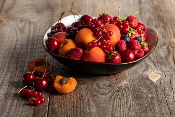 Plate with mixed delicious ripe berries on wooden table — Stock Photo