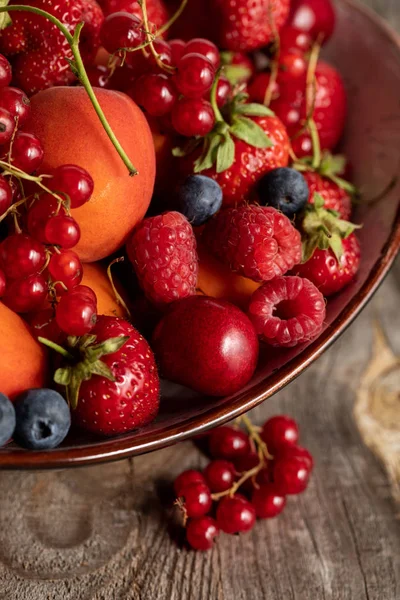 Nahaufnahme von reifen saisonalen Beeren und Aprikosen auf Teller auf Holztisch — Stockfoto