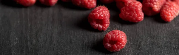 Selective focus of delicious ripe raspberries scattered on wooden table, panoramic shot — Stock Photo